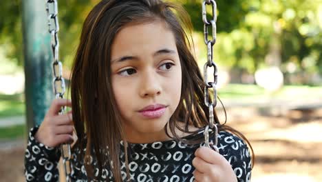 Eleven-year-old-girl-with-attitude-bullies-someone-out-of-frame-on-a-swing-set