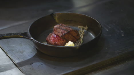 A-big,-juicy-steak-is-sizzling-in-butter-on-a-cast-iron-pan