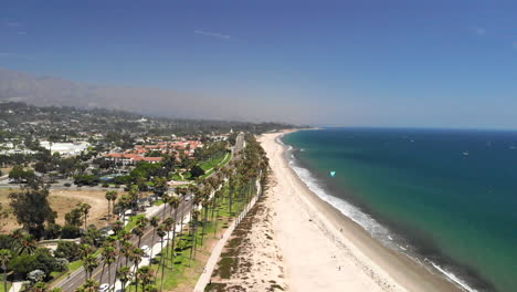Aerial-drone-shot-over-the-sandy-beach-and-the-dark-blue-Pacific-Ocean-with-kite-boarders-in-Santa-Barbara,-California