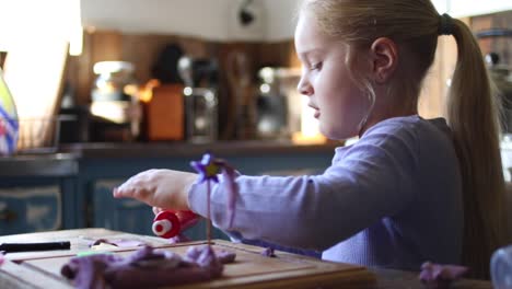 Close-up-footage-of-a-young-five-year-old-girl-playing-with-clay-in-the-kitchen-of-the-house-she-lives-in