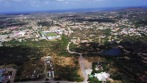 Vista-Aérea-De-Un-Lago-Natural-Y-Una-Cancha-De-Tenis-En-El-Centro-De-Aruba-Con-El-Mar-Caribe-Al-Fondo