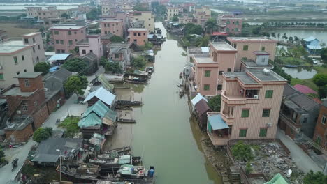 Aerial-shot-of-an-asian-village-located-along-polluted-river-with-moored-boats