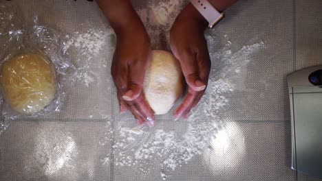 Woman-kneading-ball-of-dough-on-home-kitchen-countertop,-Close-Up-from-Above