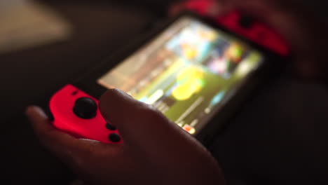 Kid-playing-a-glowing-Nintendo-Switch-at-home-in-the-dark,-Close-Up