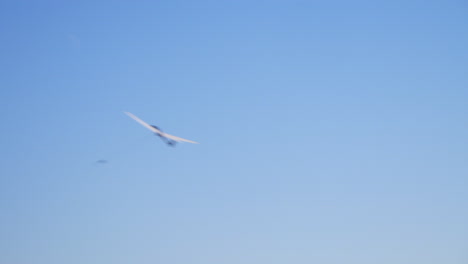 Blick-Von-Unten-Auf-Das-Startende,-Aufsteigende-Segelflugzeug-An-Einem-Drahtseil,-Das-Sich-Unter-Blauem-Himmel-Von-Rechts-Nach-Links-Bewegt