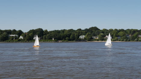 Two-sailing-boats-fight-against-drift-on-Elbe-River-in-Hamburg-at-sunny-day-and-can-not-get-forward