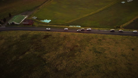 Cinematic-aerial-view-of-cars-driving-on-a-road-in-the-rural-countryside