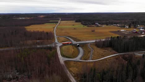 Aerial-view-of-semi-truck-driving-on-road-between-forest-and-fields