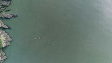 Top-down-aerial-on-three-people-in-kayaks,-one-blue-and-two-red