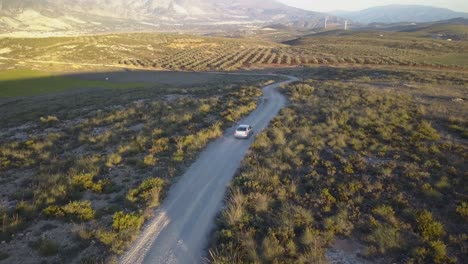 Vista-De-Seguimiento-Aéreo-De-Un-Coche-Conduciendo-Fuera-De-La-Carretera-En-El-Campo