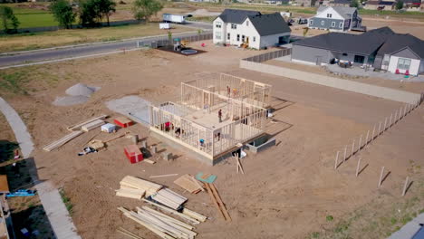 A-drone-shot-backing-away-from-framers-putting-up-walls-on-a-new-home-in-the-process-of-being-built