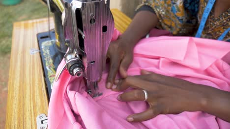 Close-up-slow-motion-shot-from-above-of-an-African-womans-hands-as-she-sews-clothing-with-a-tailoring-machine