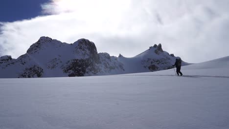 Lone-backcountry-skier-ascending-skintrack-with-jagged-ridgeline-in-background