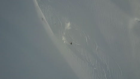 Drone-Rastreando-A-Un-Snowboarder-Cabalgando-Por-Una-Pendiente-Abierta-En-Polvo-En-El-Interior-Del-País