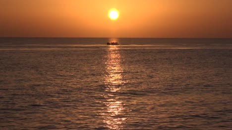 Totale-Aufnahme,-Während-Das-Boot-Langsam-Durch-Den-Orangefarbenen-Sonnenuntergang-Fährt