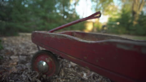 Close-up-of-the-rotten-and-broken-wood-on-an-old-damaged-child's-red-wagon