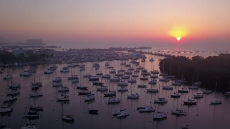 Aerial-fly-past-boat-filled-harbor-and-sunrise