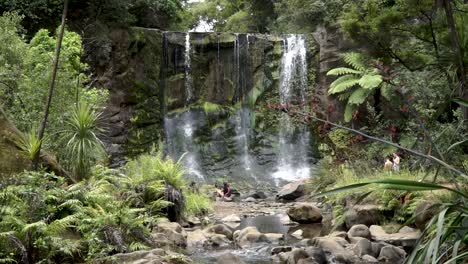 SLOWMO---People-sitting-under-Mokora-Falls,-Auckland,-New-Zealand