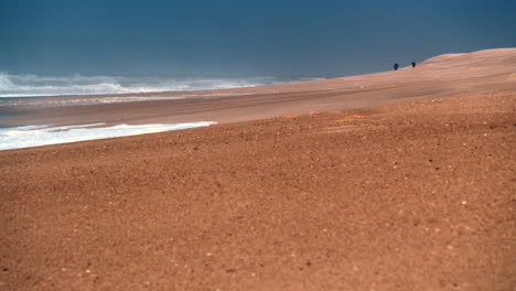 Strandlandschaft-Mit-Zwei-Menschlichen-Figuren-In-Der-Ferne-Am-Praia-Do-Norte-In-Nazare
