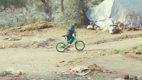 Lindo-Niño-Refugiado-Caminando-En-Su-Bicicleta-Verde-Brillante-Antes-De-Subir-Y-Bajar