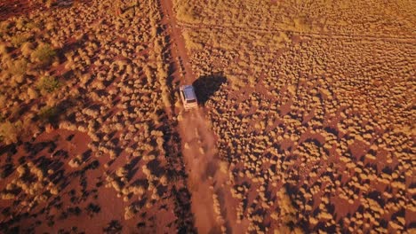 Aerial-Drone-bird-eye-top-following-4WD-Truck-down-gravel-road-in-Australian-Desert-after-bushfire