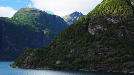 massive-Geiranger-Fjord-scenery,-as-seen-from-a-cruise-ship,-big-mountains-reaching-out-of-the-blue-water-in-4k