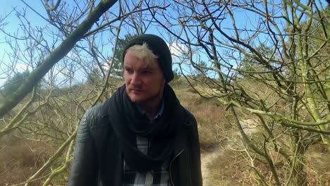 Extreme-slow-motion-tracking-shot-of-an-authentic-bearded-hipster-man-walking-through-the-woods-on-a-sunny-day