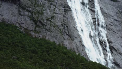 Norway-landscape,-big-waterfall-close-up-moving-down-the-rocks-with-green-forest-below