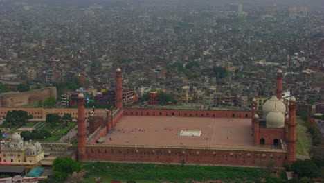 Lahore,-Pakistan,-Aerial-view-of-heritage-Badshahi-Mosque-with-city-view,-the-oldest-Mosque-by-the-Mughal-Emperors,-black-kites-flying,-Four-Minarets-of-the-Mosque