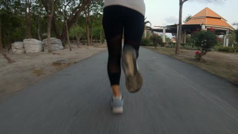 A-slowmotion-follow-up-shot-of-a-young-thai-girl-jogging-in-a-local-park-,-the-shot-is-focused-on-her-legs-as-she-runs-forward