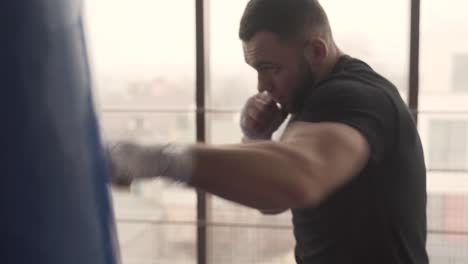 Alone-boxer-is-hitting-punching-bag-very-fast-in-the-fitness-studio