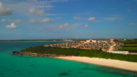Aerial-pan-shot-of-a-new-settlement-inf-ront-of-a-tropical-beach-with-turquoise-water,-Miyakojima,-Okinawa,-Japan