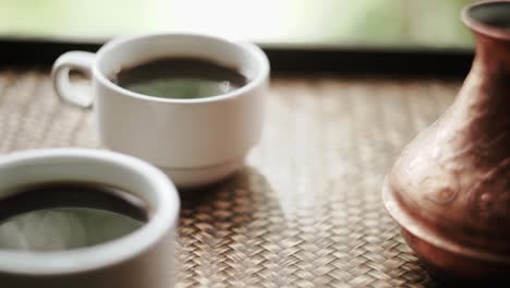 Coffee-cups-and-cezve-with-Turkish-coffee-close-to-window-with-view-on-green-trees-close-up-slow-motion