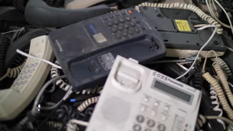 Close-up-of-stack-used-office-phones-sorted-for-recycling