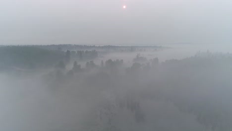 Vista-Aérea-Volando-A-Través-De-La-Niebla,-El-Humo-Y-Las-Nubes-En-Una-Alberta-Rural-Con-Un-Sol-Rojo-En-El-Horizonte