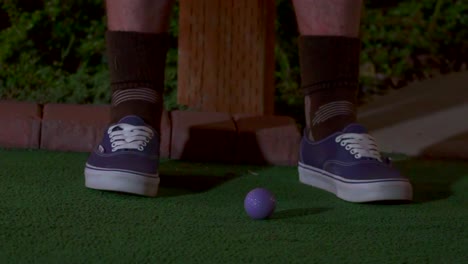 A-slow-motion-close-up-of-a-purple-mini-golf-ball-getting-hit-with-a-club