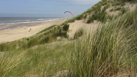 A-singe-paraglider-with-a-red-wing-is-leisurely-soaring-over-the-dunes-at-a-north-sea-beach
