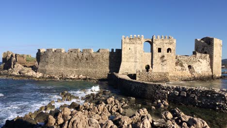 Methoni-Castle-with-a-bridge-in-sunny-weather-during-early-morning-hours-with-water-waves-in-Greece