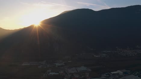 Drone-in-Monte-Grappa-mountains-revealing-colorful-sunset-with-flares-near-Verona,-Bassano-del-Grapa,-Italy