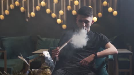 Guy-sitting-on-the-couch-and-smoking-hookah
