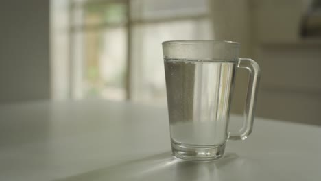 Pouring-hot-water-from-a-kettle-to-glass-mug-at-home