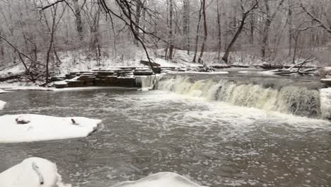 A-slow-motion-side-view-of-a-snow-and-ice-covered-river-in-nature-during-winter