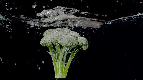 Colorful-branch-of-broccoli-being-dropped-into-water-in-slow-motion
