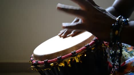 Medium-wide-looking-down-isolated-shot-of-a-man-playing-djembe-drum-alone-in-a-dark-room