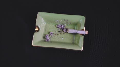Smoking-and-Ashing-a-Rolled-Cigarette-or-Joint,-legalised-marijuana-on-green-Ashtray