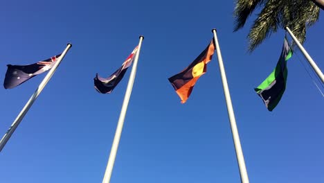 Slow-motion-shot-of-the-four-flags-outside-Queensland-Parliament-House-fluttering-in-the-wind,-in-Brisbane,-Australia