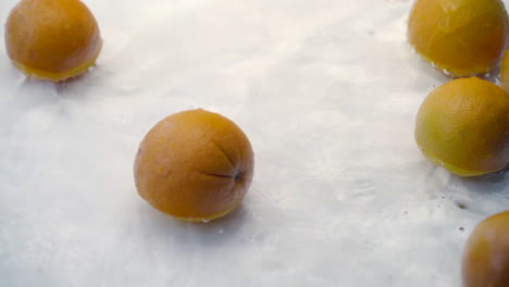 SLOMO-of-Oranges-Falling-into-Water-on-White-Backdrop