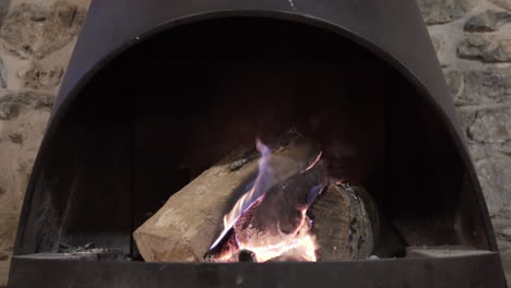4K-clip-of-a-beautiful-wood-fire-burning-inside-a-traditional-rural-black-l-fireplace-in-a-winter-house