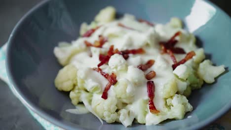 Seasoning-cooked-cauliflower-in-gray-bowl-with-fried-bacon-and-bryndza-cheese