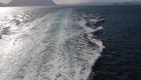 tilt-wide-slow-motion-shot-from-cruise-ship-for-the-ocean-with-far-mountain-islands-in-background